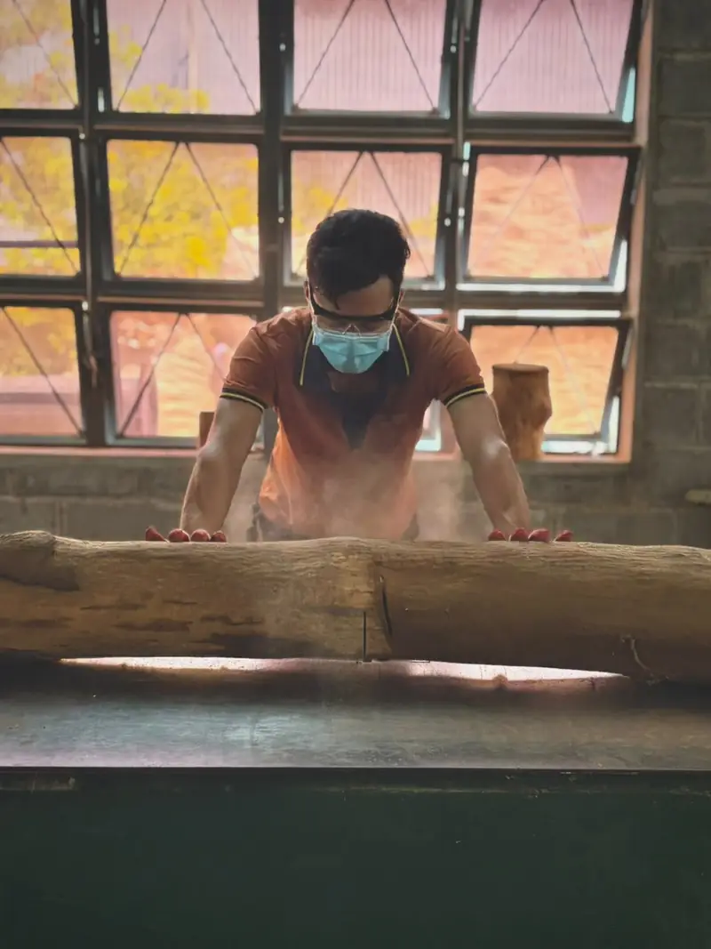 A craftsman working a sandalwood log at the bench